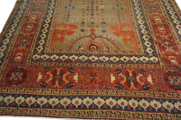 Low pile rug featuring a tan field with rust patterns, surrounded by complex red and dark blue borders.