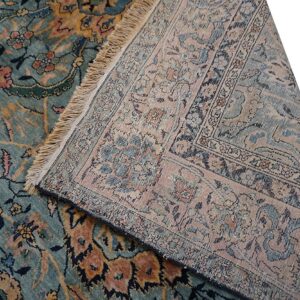 The teal, pink, and gold patterned rug face is displayed next to its muted, flatwoven reverse side and fringe.