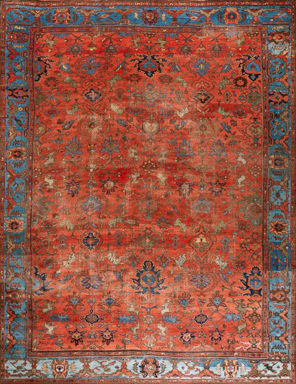 Distressed red rug with an all-over intricate pattern and wide, decorative turquoise blue border.