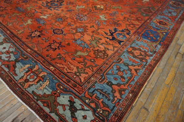 Terracotta rug featuring blue, teal, and navy floral patterns shown on distressed wood flooring.
