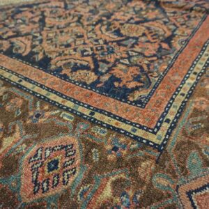 Close-up of a rug showing intricate traditional patterns in navy, terracotta, and brown.