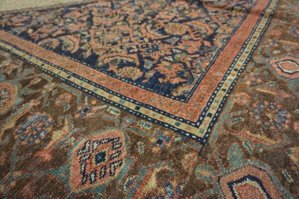 Close-up of a rug showing intricate traditional patterns in navy, terracotta, and brown.