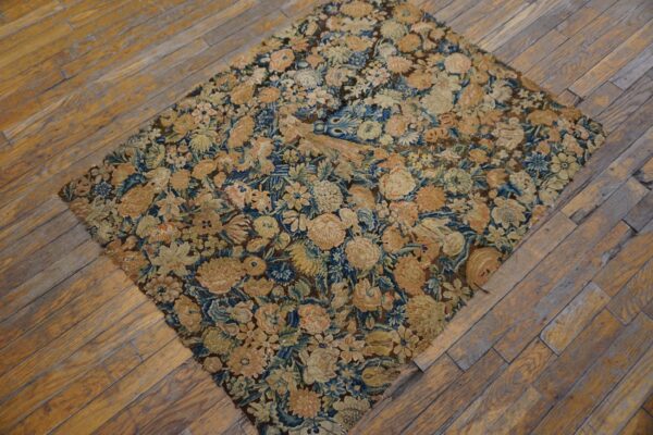 Muted floral rug featuring gold and blue tones placed diagonally on distressed wood flooring.