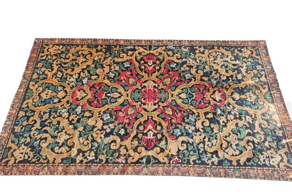 A large rug displays ornate scrolling floral patterns in gold, red, blue, and green on a dark background.