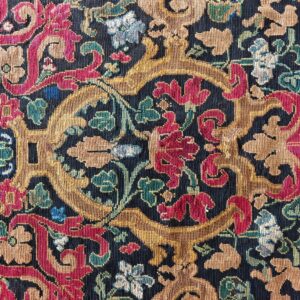 Detailed view of a low-pile rug with red, gold, and green baroque floral motifs on a navy ground.