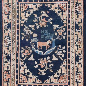 Dark blue rug with a beige and coral floral border surrounding a central medallion with an orange animal.