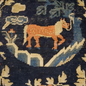 Stylized animal and floral pattern in rust, pale blue, and tan on a deep indigo rug background.