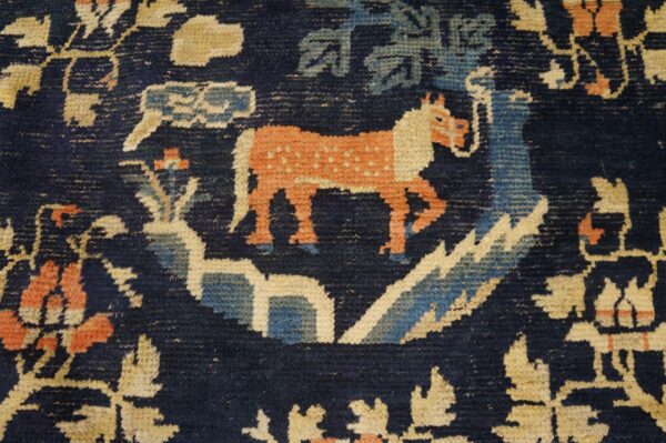 Stylized animal and floral pattern in rust, pale blue, and tan on a deep indigo rug background.