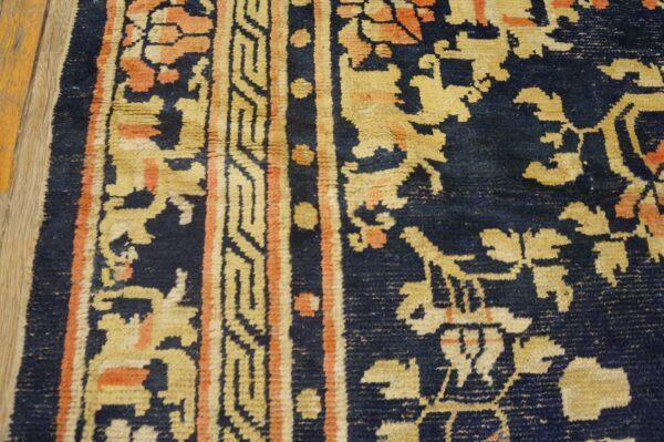 A close-up shows a navy rug with shaggy gold and orange traditional patterns on wood flooring.