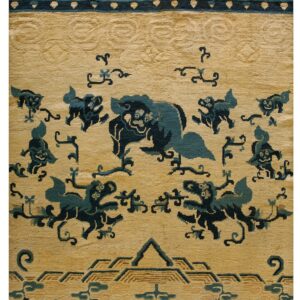 Tan and dark blue rug detail showing stylized mythological animals, cloud motifs, and a geometric key border.