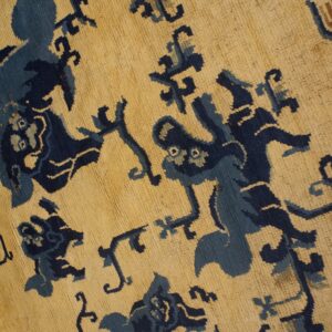High-pile rug with stylized navy and light blue designs on a tan ground, visible over wood flooring.