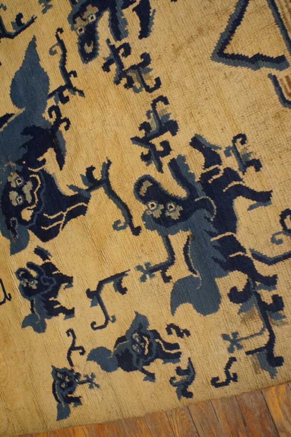 High-pile rug with stylized navy and light blue designs on a tan ground, visible over wood flooring.