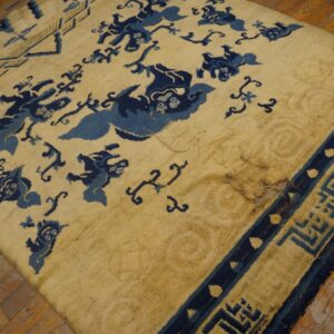 Worn yellow rug with dark blue animal and geometric patterns sits on rustic wood planks.