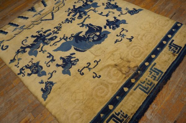 Worn yellow rug with dark blue animal and geometric patterns sits on rustic wood planks.