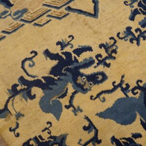 Textured beige rug with abstract dark and light blue motifs lies on warm-toned hardwood planks.