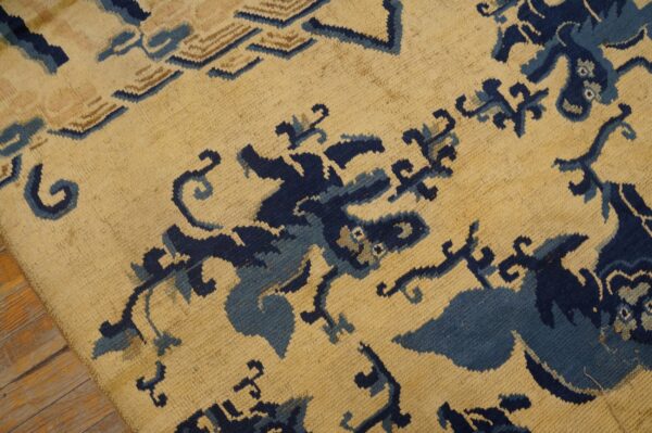 Textured beige rug with abstract dark and light blue motifs lies on warm-toned hardwood planks.