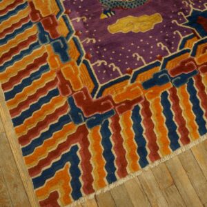 Purple rug with yellow clouds and geometric orange, blue, and red border on wood planks.