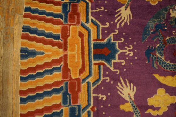 A purple, red, yellow, and blue patterned rug with dragon and geometric motifs borders a wooden floor.