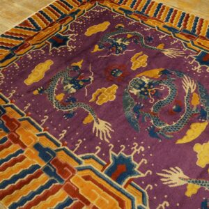 Purple dragon rug with yellow accents and a bold geometric border in orange, red, and blue on a wood floor.