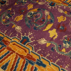 Purple dragon-patterned rug with blue, yellow, and red accents, featuring a multi-colored geometric border on wood flooring.