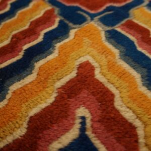 A detailed view of a plush rug featuring multicolored wavy chevrons outlined in cream.