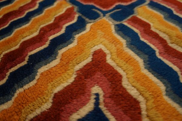 A detailed view of a plush rug featuring multicolored wavy chevrons outlined in cream.