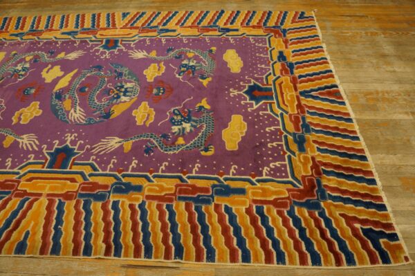 Purple dragon-patterned rug with bold red, blue, and gold borders lying on worn light wood flooring.