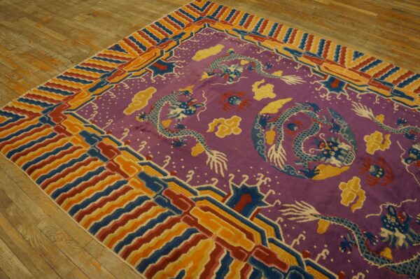 Magenta rug with blue dragon pattern and multicolored striped borders rests on a wooden floor.