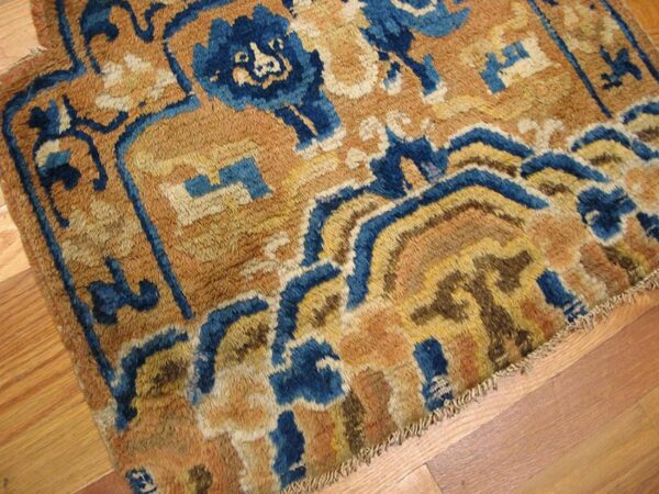 Shaggy, high-pile rug with blue and gold abstract patterns rests on light hardwood planks.