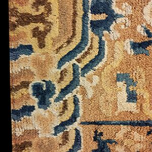 The rug has a dense pile texture featuring wavy blue and brown abstract motifs on a golden background.