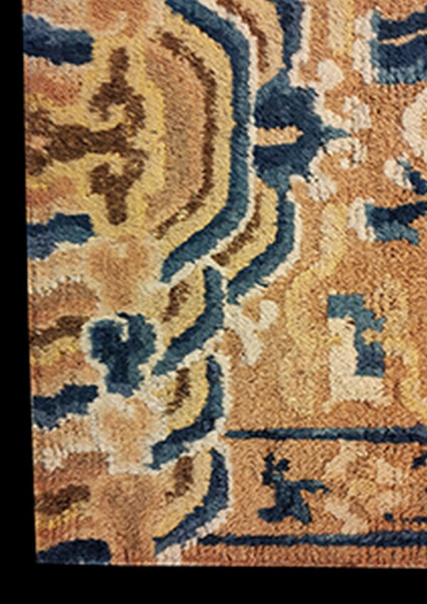 The rug has a dense pile texture featuring wavy blue and brown abstract motifs on a golden background.