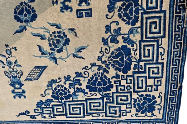 Cream field rug with deep blue floral patterns and greek key border details.