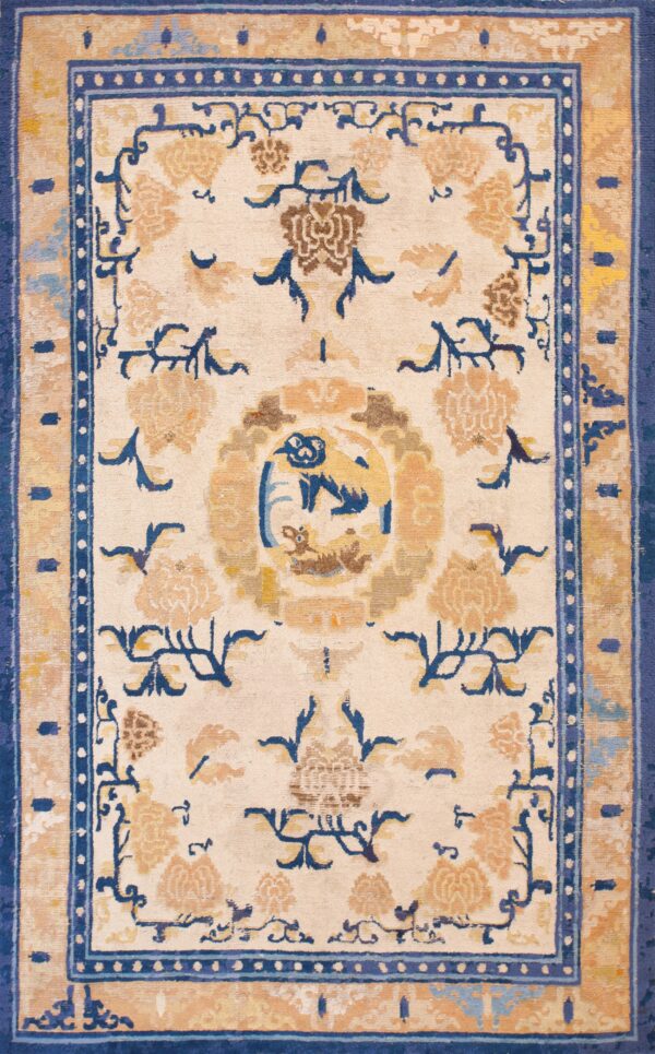 Cream rug featuring a bold blue and tan border with stylized florals and a central animal design.