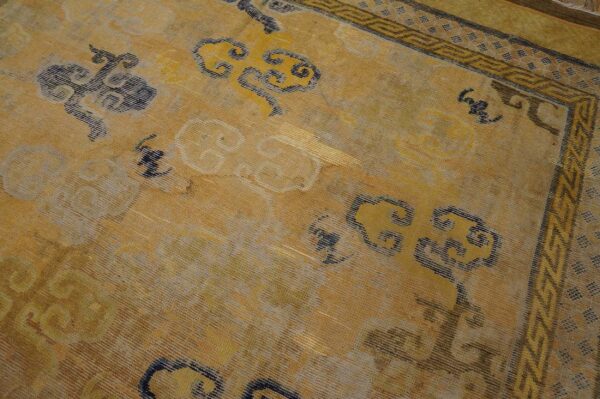 Gold and yellow rug featuring stylized blue and gray cloud motifs and a detailed geometric border.