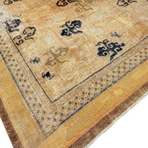 Distressed gold and beige rug corner showing navy cloud motifs and complex geometric borders.