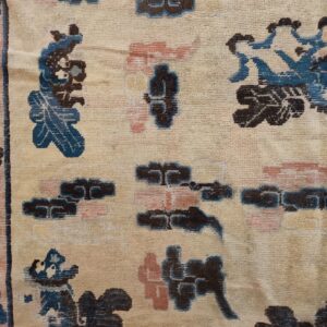 Low-pile rug detail featuring a beige background and scattered, stylized motifs in navy, pink, and teal blue.