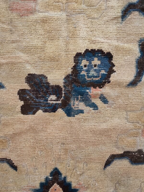 Textured beige high-pile rug detail showing stylized dark blue and brown figures against a light background.