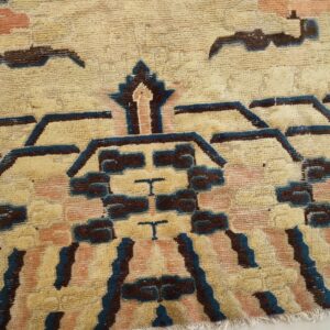 Textured beige rug featuring large geometric patterns outlined in dark blue and filled with brown and peach.