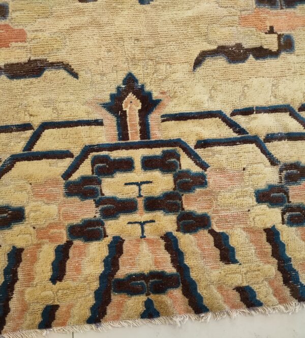 Textured beige rug featuring large geometric patterns outlined in dark blue and filled with brown and peach.