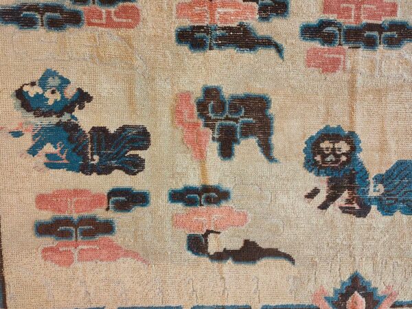 Beige rug detail showing stylized dark brown, teal, and pink cloud and animal motifs.
