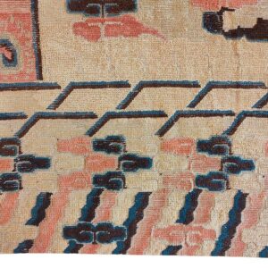 Textured rug detail with abstract motifs in beige, salmon, dark brown, and teal blue.