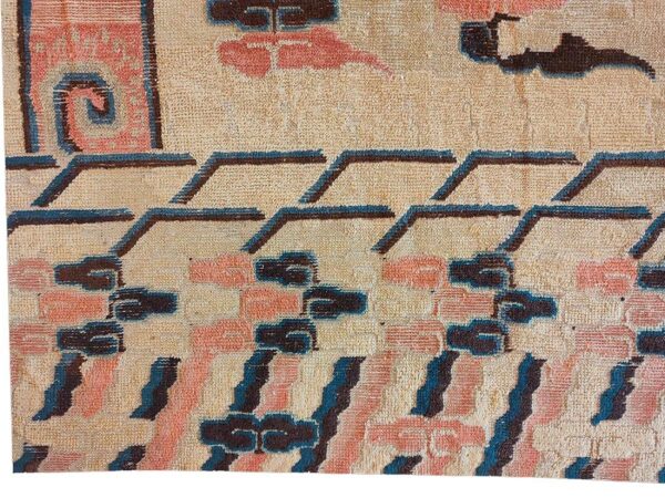 Textured rug detail with abstract motifs in beige, salmon, dark brown, and teal blue.