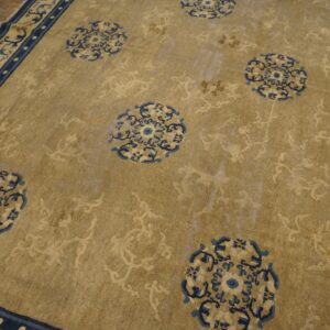 Khaki rug with scattered blue medallions and a detailed navy border rests on wood flooring.