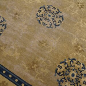 Distressed tan rug with dark blue circular motifs and a dotted border stripe in the corner.