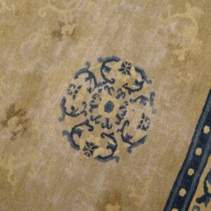 Distressed gold rug detailed with a central dark blue medallion and a vertical dotted border.
