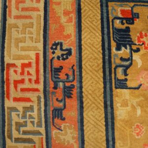 Plush rug border in navy, coral, and gold with geometric patterns rests on hardwood flooring.