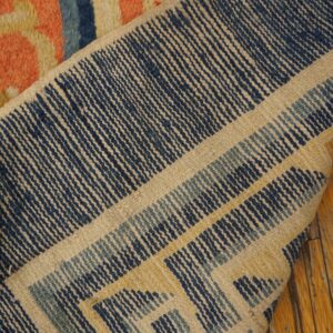 A folded rug displays a textured coral front and a tightly woven navy and cream geometric back.