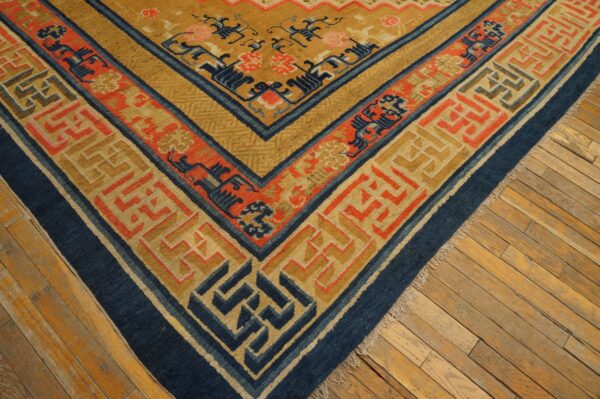 Gold, blue, and coral patterned rug corner on distressed wood flooring.