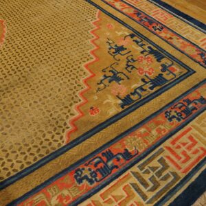 Golden patterned rug with navy blue and coral borders, featuring a partial white bird motif on hardwood floor.
