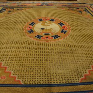 Gold rug with a trellis pattern, large bird medallion, and navy blue and coral angular borders on wood flooring.